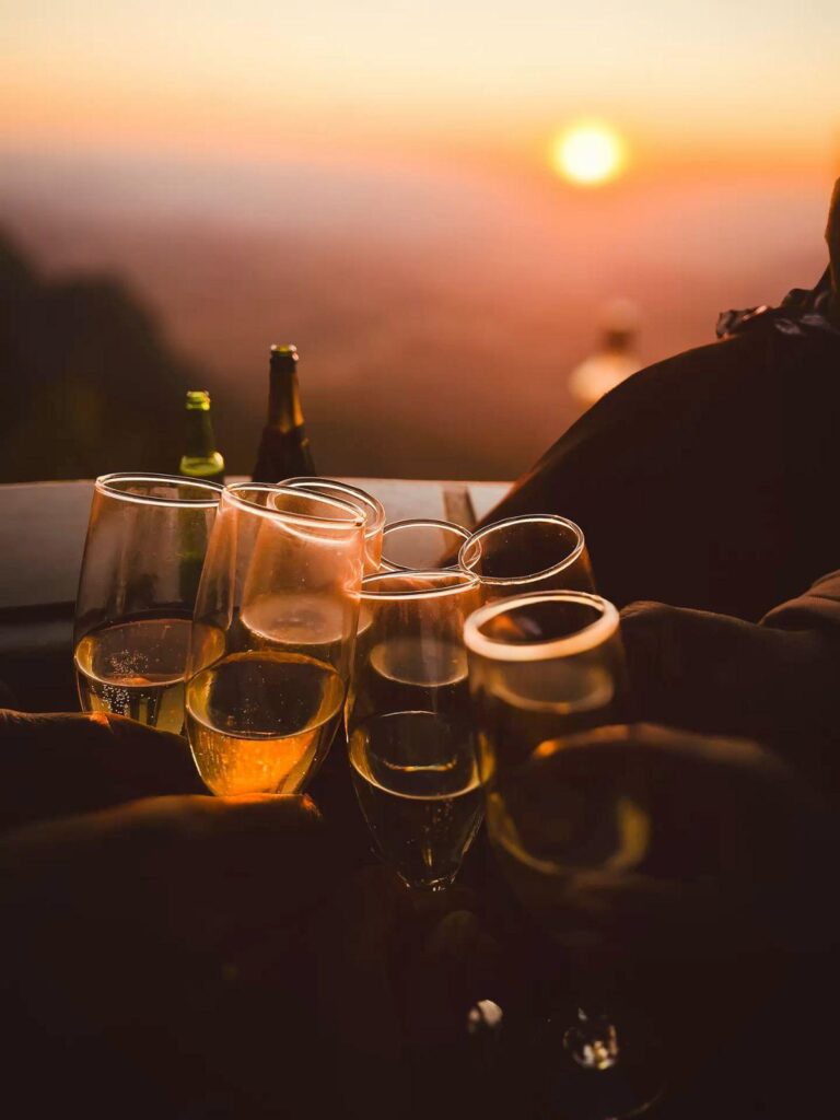 Group of people clinking glasses of champagne against a sunset backdrop